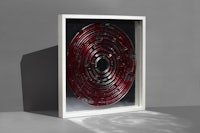 a framed piece of glass with a red spiral in it